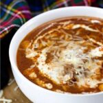 Bowl of low carb lasagna soup with melted cheese next to a tartan napkin