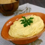 Creamy butternut squash dip in an orange serving dish topped with fresh parsley
