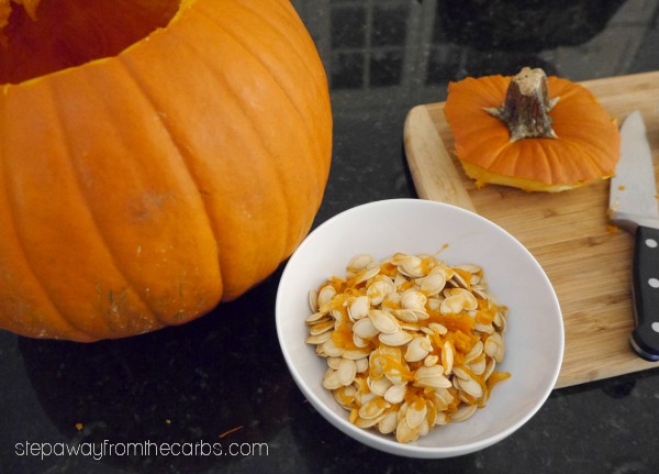 Roasted Pumpkin Seeds in a  bowl next to a pumpkin 