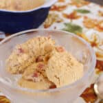 Scoops of keto pumpkin ice cream with candied bacon in a glass dessert dish on an autumn leaf tablecloth