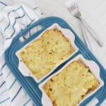 Two baked low carb chicken pot pies with golden cauliflower crust on a blue tray