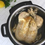 Whole poached chicken in an Instant Pot with lemons and parsley