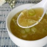 Low carb egg drop soup in a white bowl with a spoonful of egg ribbons and the recipe title
