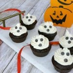 Low carb ghost cupcakes with cream cheese frosting and chocolate chip faces next to a jack-o-lantern
