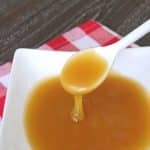 Low carb caramel sauce dripping from a spoon into a white bowl