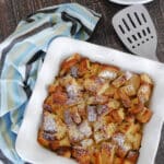 Keto French toast casserole in a white square baking dish, dusted with powdered sweetener