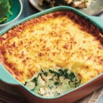 Keto creamy chicken spinach bake in a teal baking dish, with a serving cut out to show the chicken and spinach