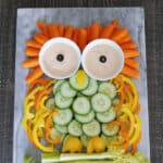 Owl veggie tray made from baby carrots, cucumber slices, bell peppers and celery on a marble board
