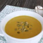 Bowl of keto coconut curry soup topped with pepitas on a teal napkin