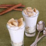 Two shot glasses of keto cinnamon toast dessert topped with Catalina Crunch cereal pieces, with cinnamon sticks and spoons