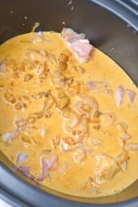 Coconut milk curry sauce poured over raw chicken in a slow cooker