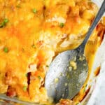Low carb cheesy ham cauliflower casserole in a glass baking dish with a serving spoon