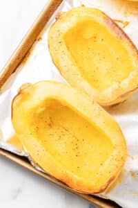 Roasted spaghetti squash halves on a foil-lined baking sheet