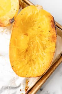 Fork scraping roasted spaghetti squash into noodle-like strands