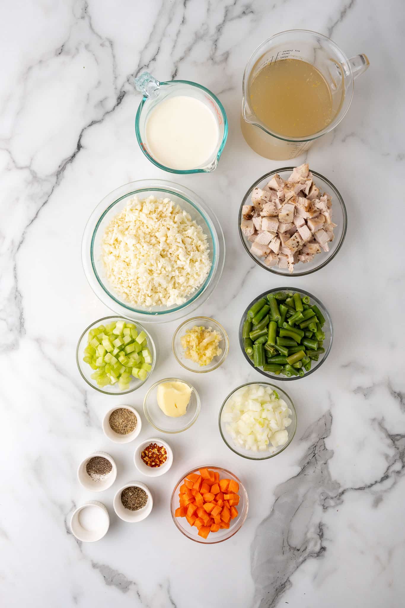 Ingredients for keto turkey soup measured into bowls on a marble counter