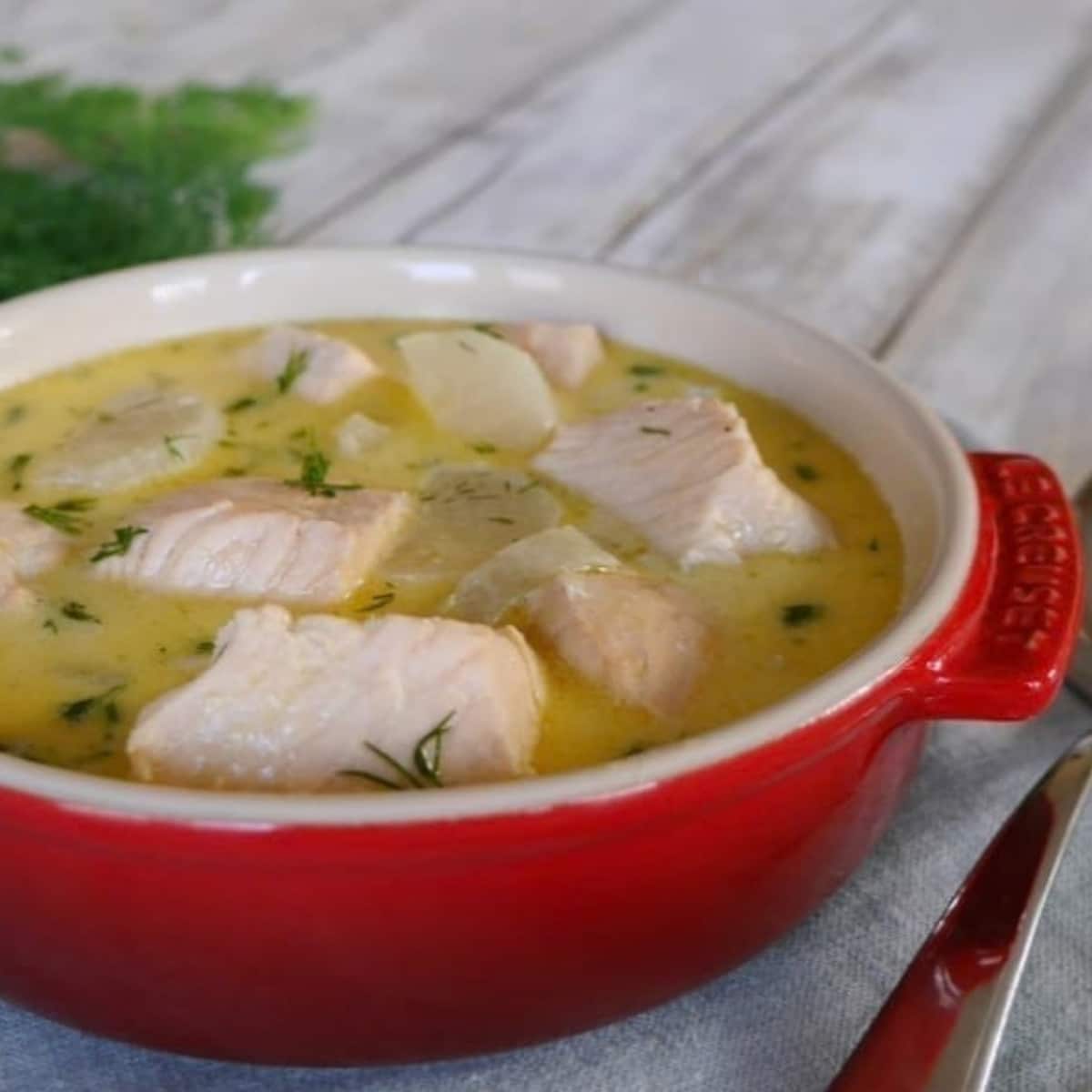 Keto salmon soup with daikon radish and dill in a red bowl