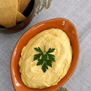 Butternut squash dip in an orange dish garnished with parsley