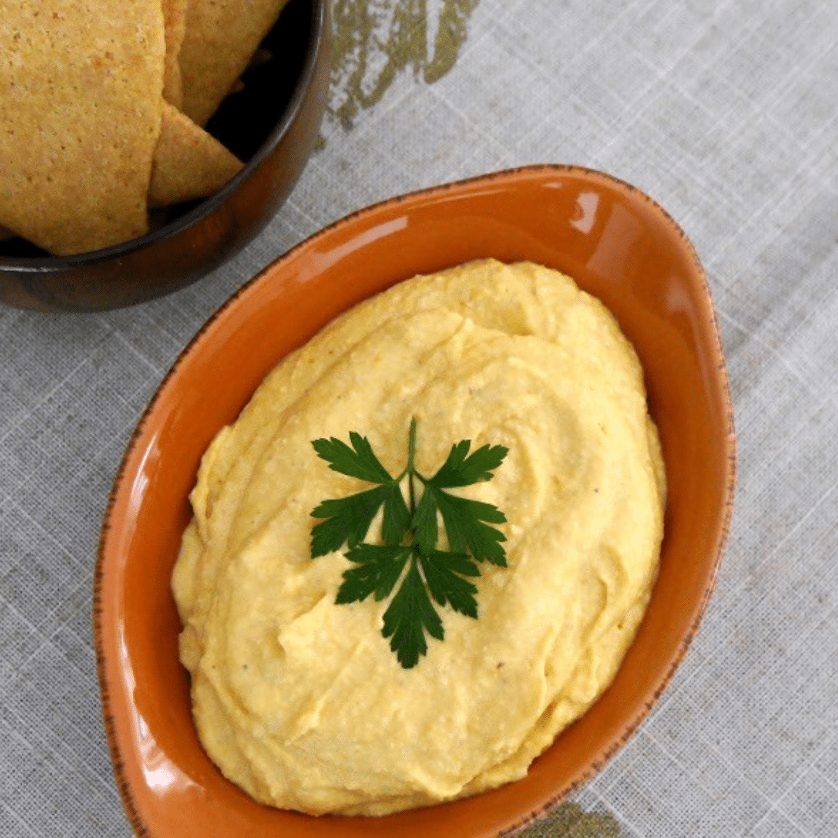 Butternut squash dip in an orange dish garnished with parsley