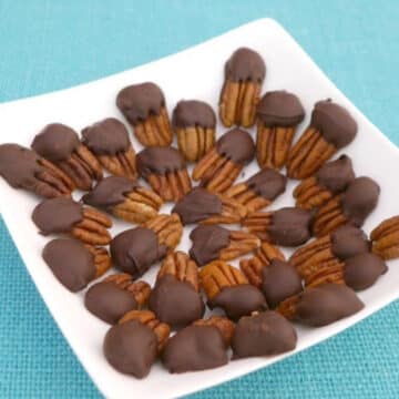 Sugar free chocolate covered pecans on a white square plate
