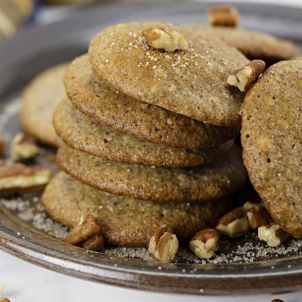Stack of easy low carb pecan cookies on a rustic plate with chopped pecans