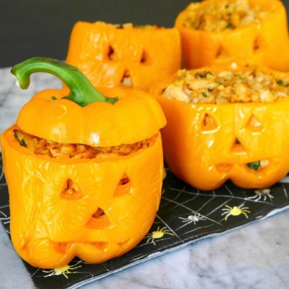 Halloween stuffed peppers: orange bell peppers carved like jack-o'-lanterns and filled with chicken and cauliflower rice