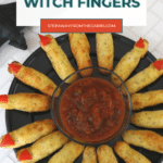 Halloween witch fingers on a black platter around a bowl of salsa