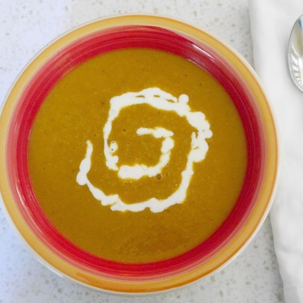 Bowl of Indian butternut squash soup with a swirl of sour cream