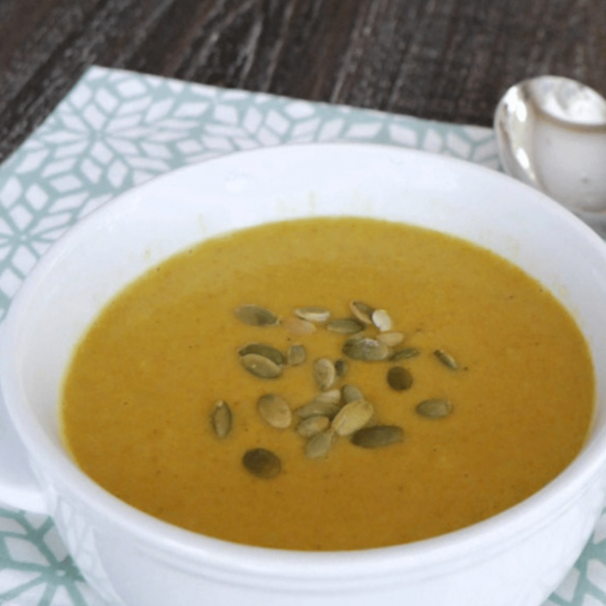 Keto coconut curry soup in a white bowl topped with pepitas