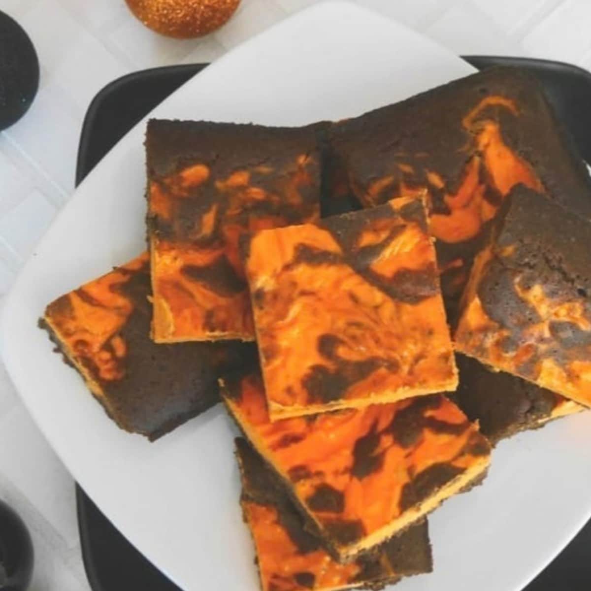 Keto Halloween brownies with an orange cheesecake swirl on a white plate