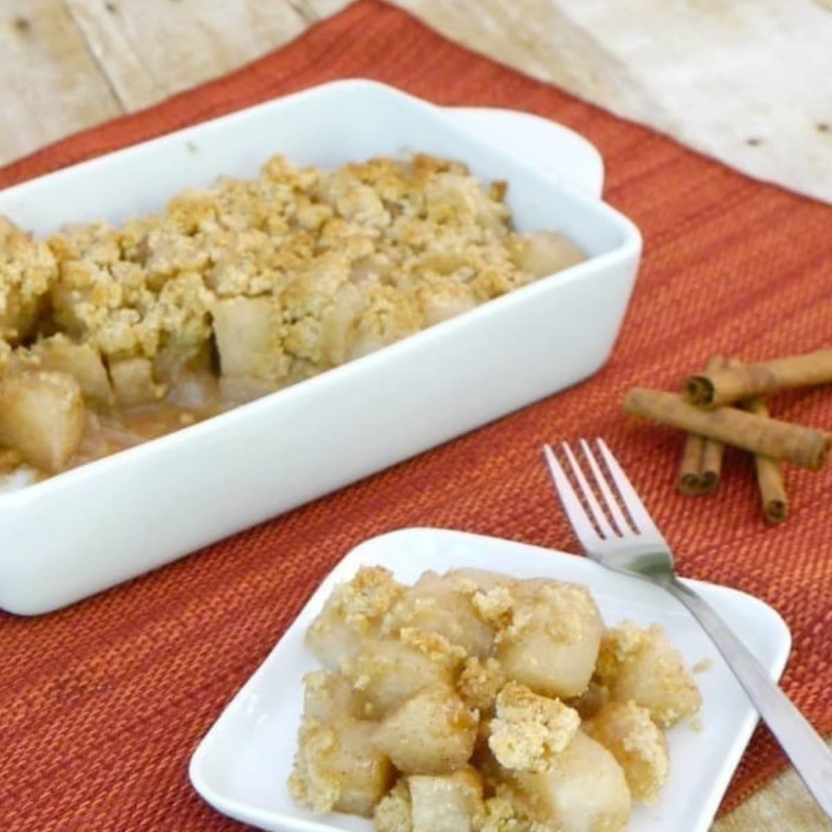 Low carb apple crumble made with jicama in a white baking dish with a serving on a plate