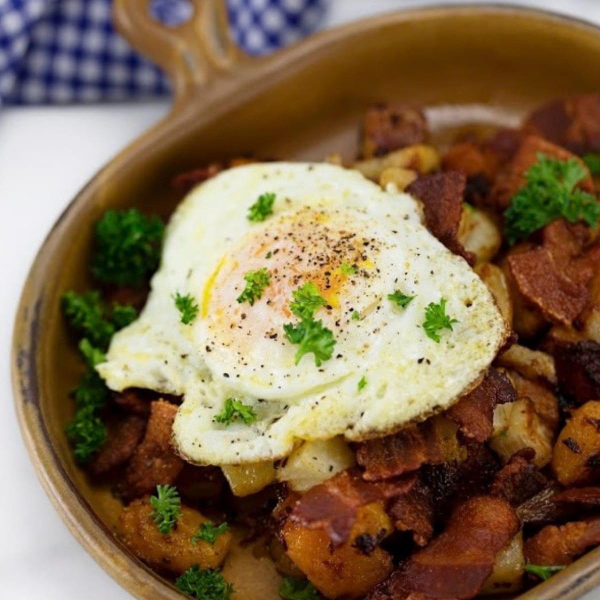 Low carb butternut squash hash with crispy bacon and a fried egg in a ceramic skillet