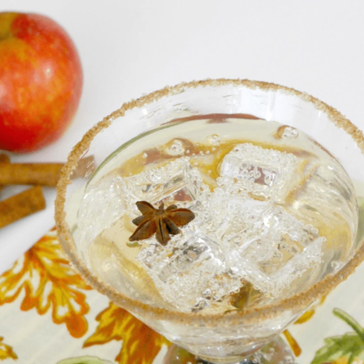 Low carb caramel apple cocktail with ice and a star anise in a cinnamon-rimmed glass