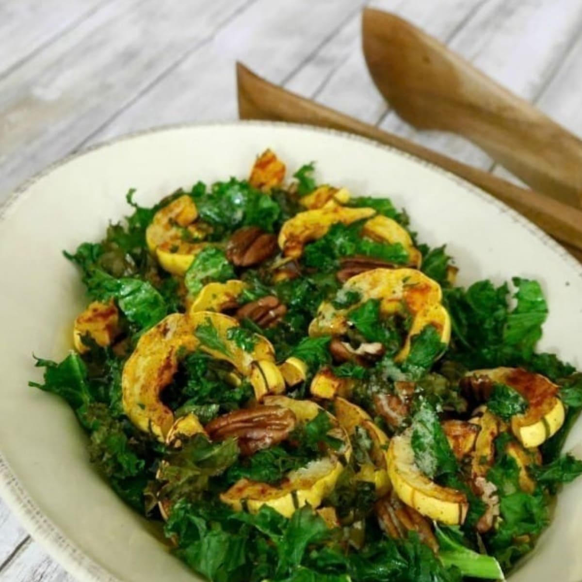 Roasted delicata squash rings with kale and pecans in a white serving bowl