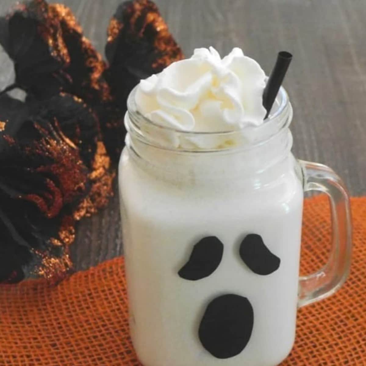 Low carb ghost milkshake in a mason jar mug decorated with a black ghost face and topped with whipped cream