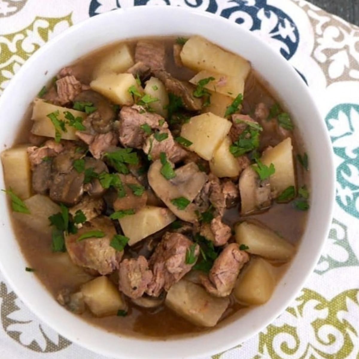 Low carb lamb stew with turnips, mushrooms and parsley in a white bowl