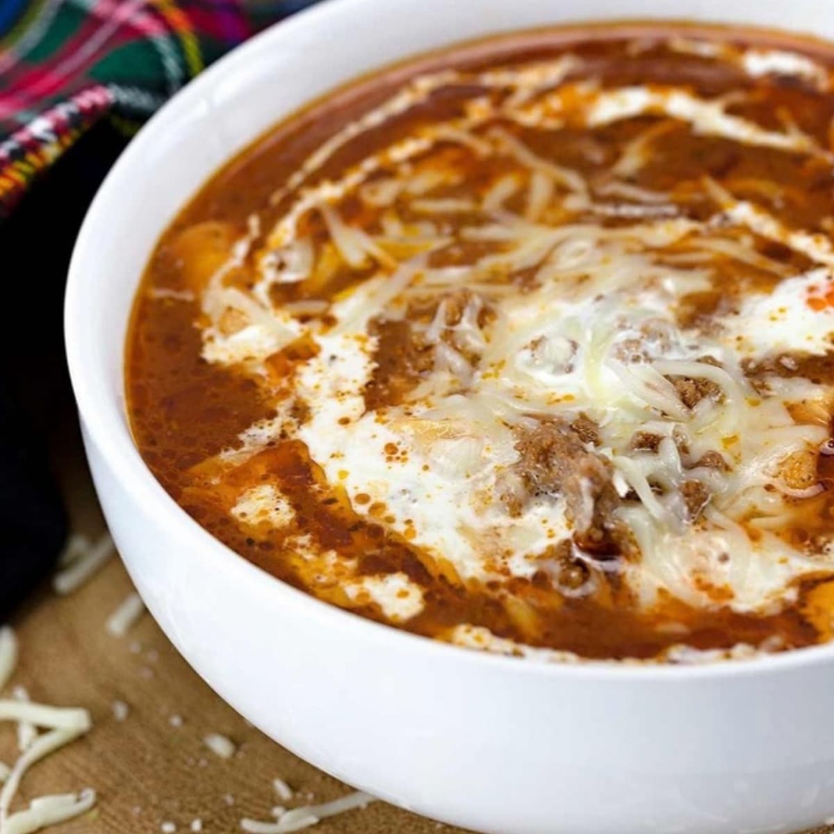 Low carb lasagna soup in a white bowl topped with melted cheese and cream
