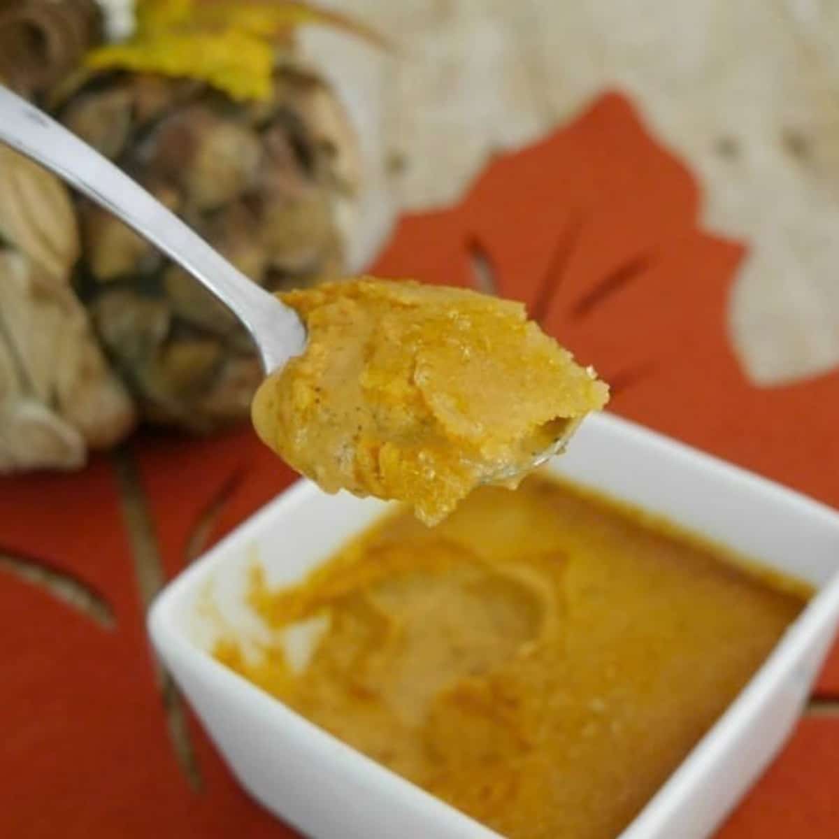 Low carb pumpkin pie creme brulee in a white square ramekin with a spoonful lifted out