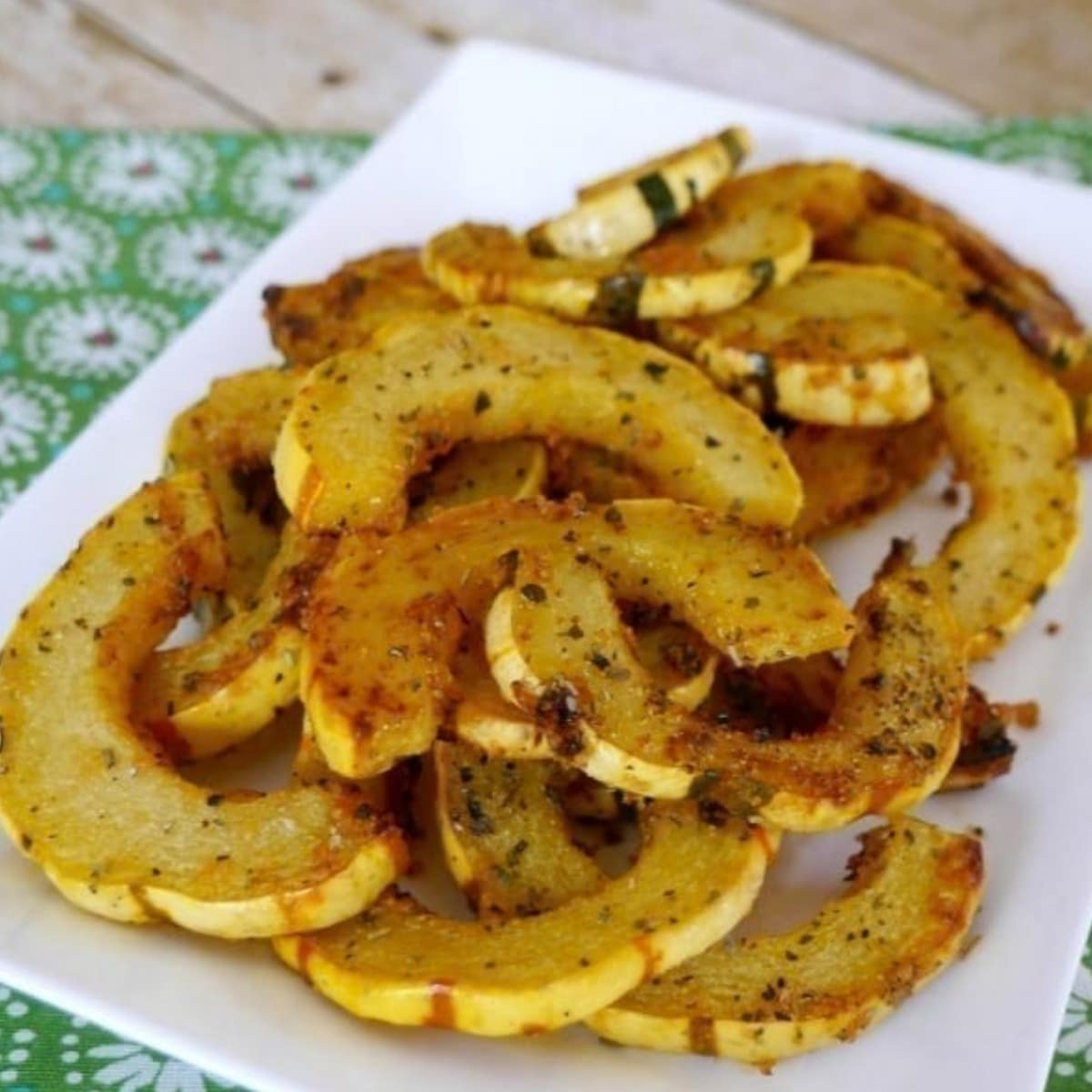 Roasted delicata squash slices with Parmesan and herbs on a white plate