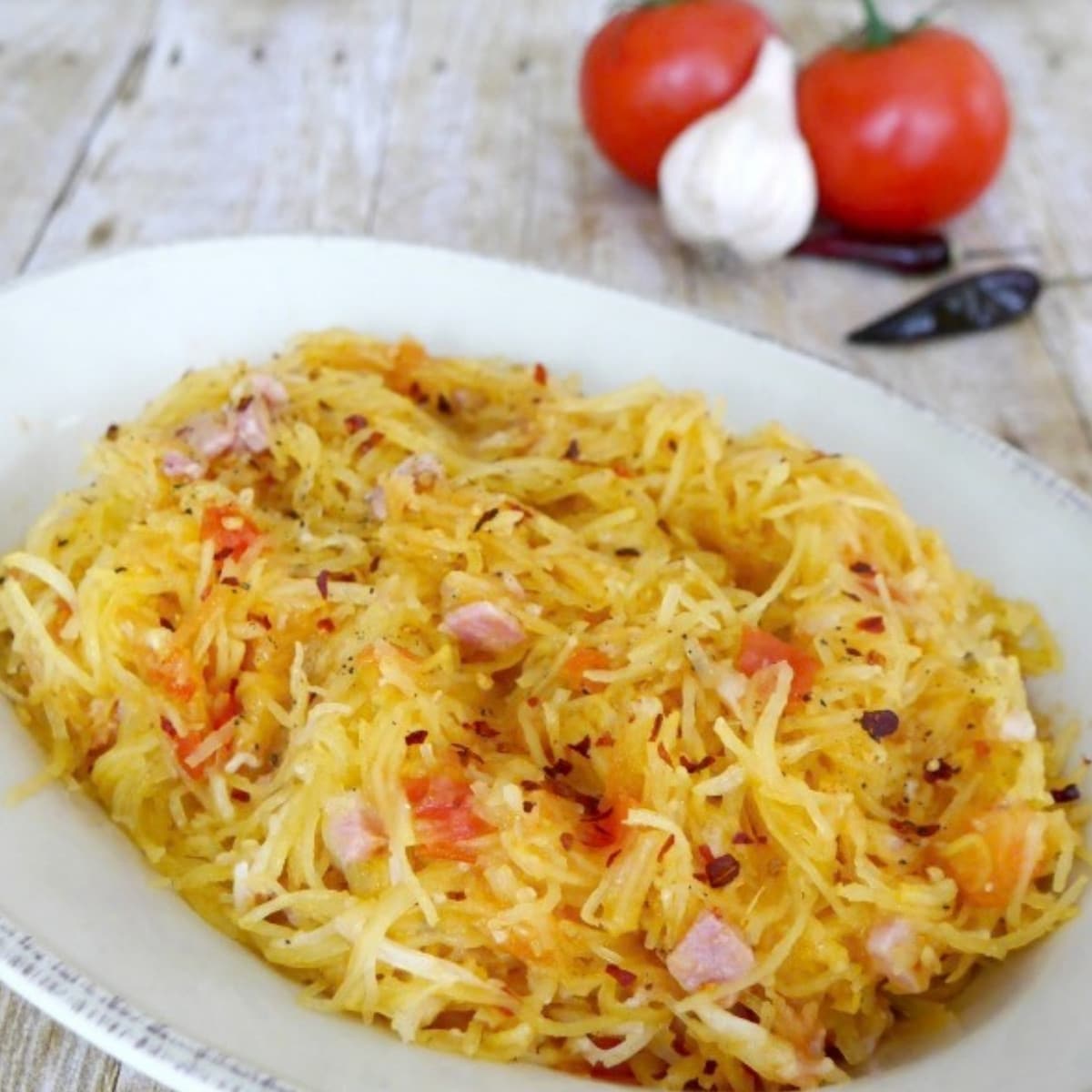 Spaghetti squash all'arrabbiata with pancetta, tomatoes and red pepper flakes in a white bowl