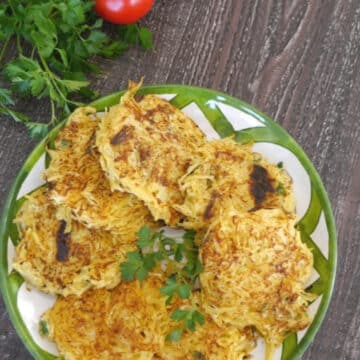 Spaghetti squash fritters on a green and white plate with fresh parsley