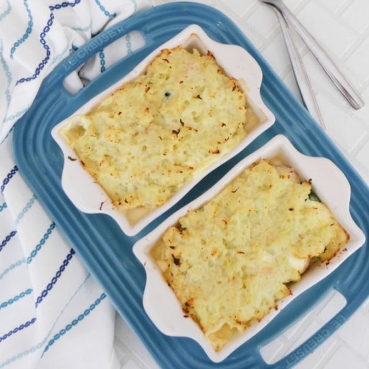 Two low carb chicken pot pies with a golden mashed cauliflower crust on a blue serving tray