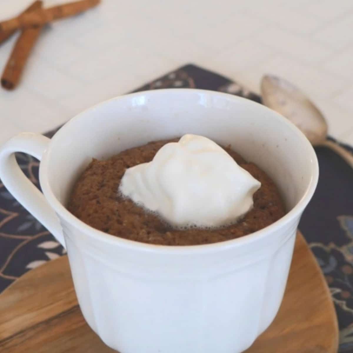 Low carb chocolate mug cake topped with whipped cream in a white cup