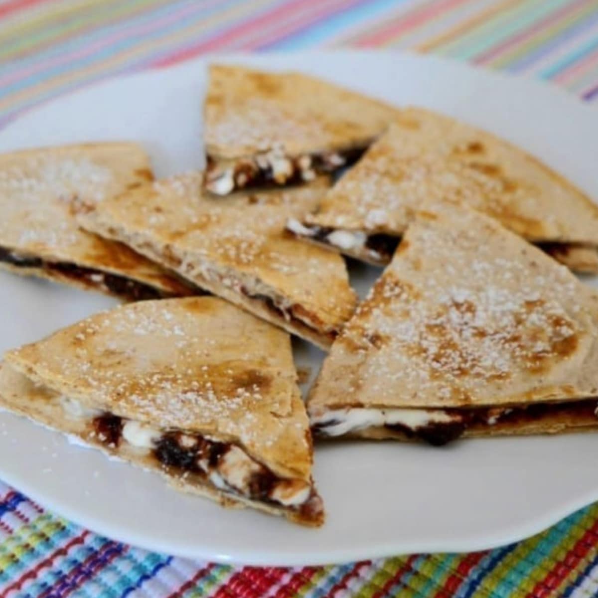 Low carb chocolate quesadilla wedges dusted with powdered sweetener on a white plate