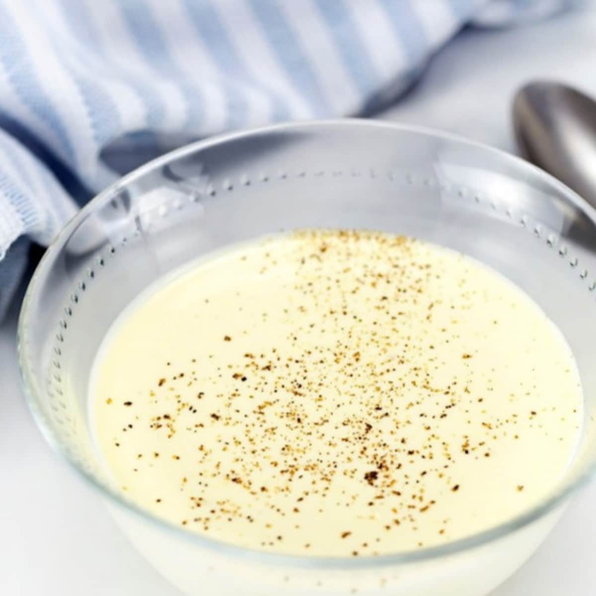 Low carb white sauce in a glass bowl topped with cracked black pepper