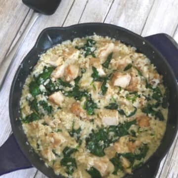 One pot chicken and cauliflower rice casserole with spinach in a blue cast iron skillet
