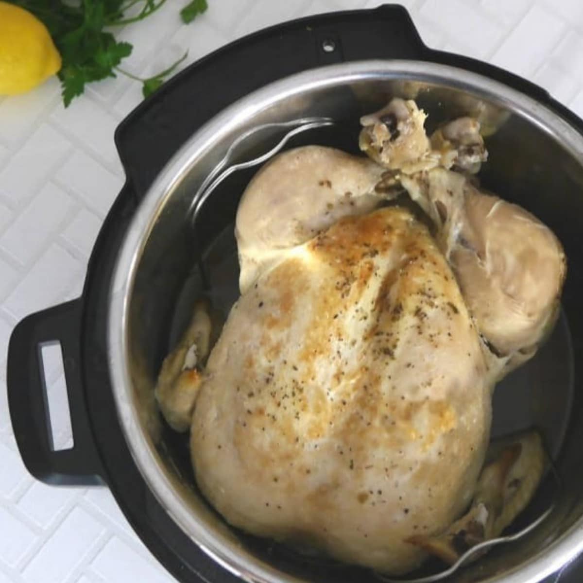 Whole poached chicken in an Instant Pot with lemons and parsley